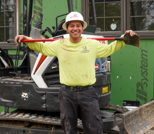 a man holding a shovel in front of a bobcat