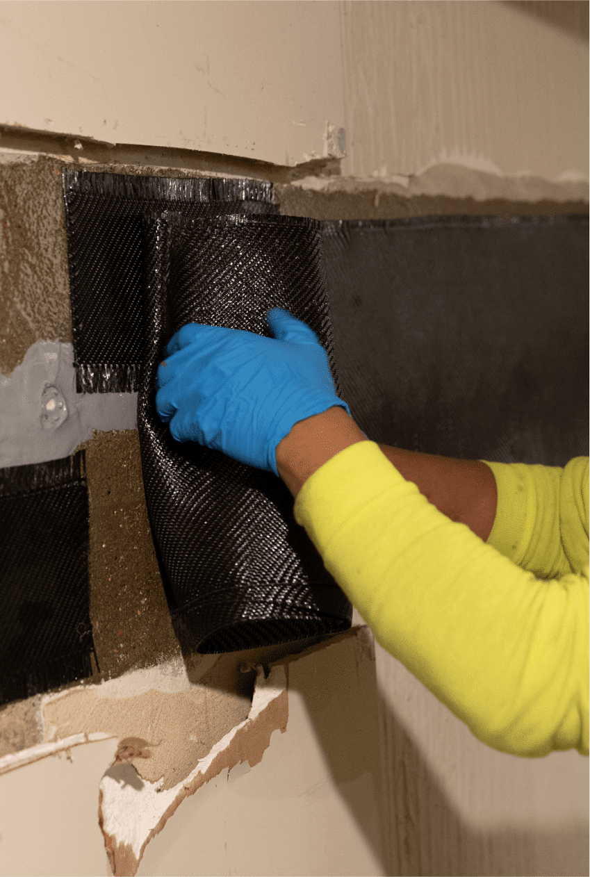 a man repairing a foundation with supplies in his gloved hands