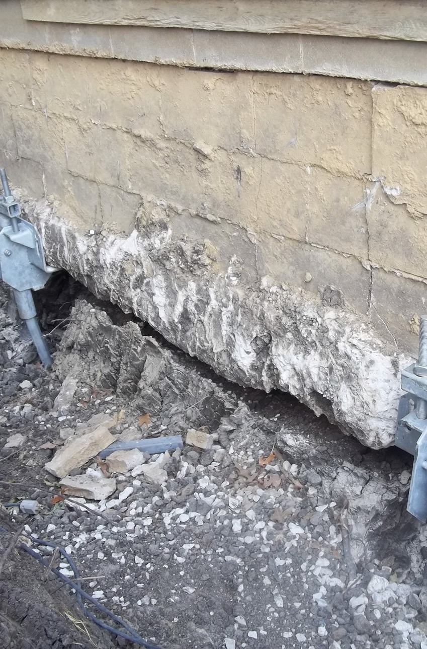 a damaged foundation with pieces crumbling into the soil