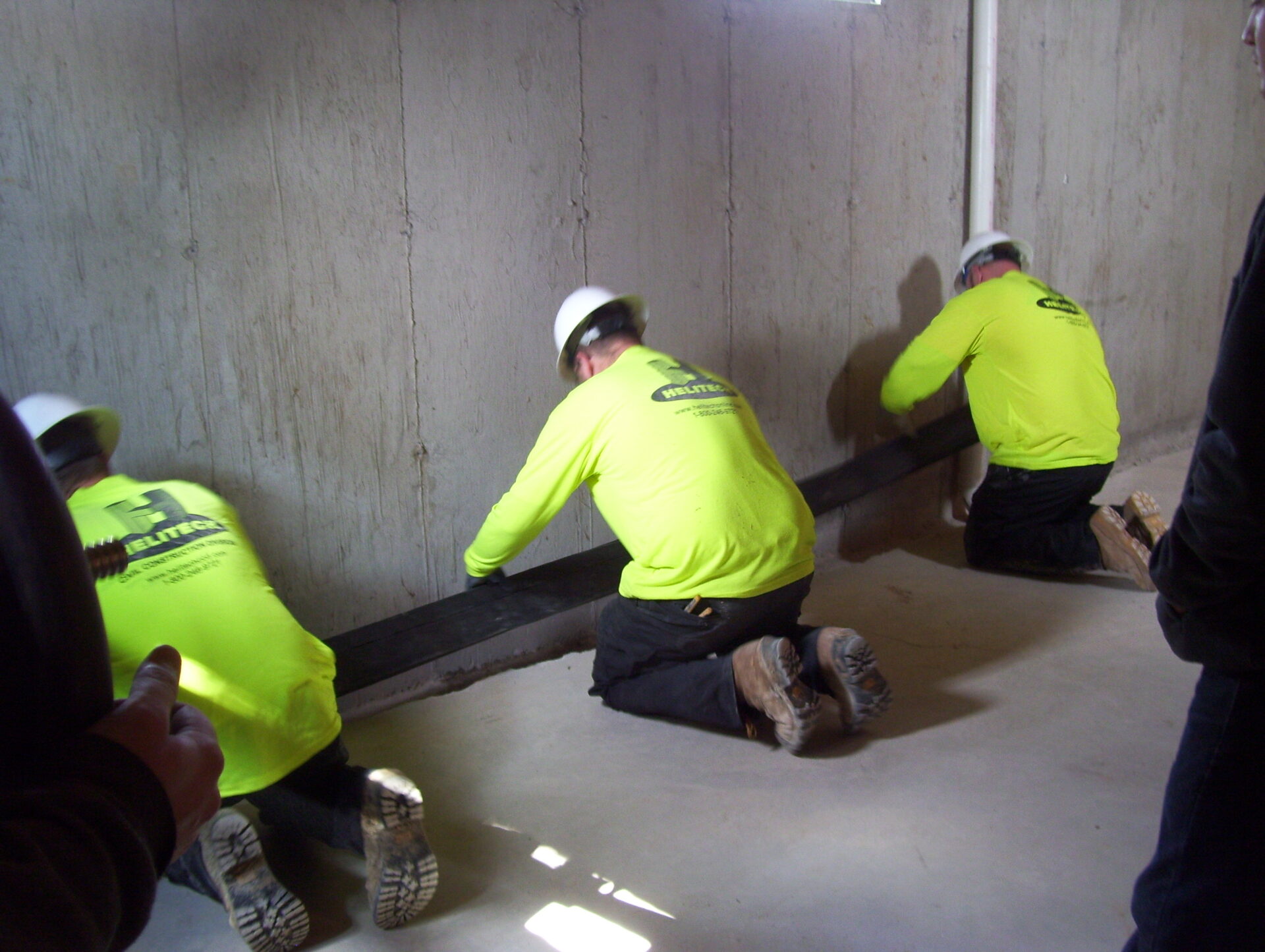 three men waterproofing basement